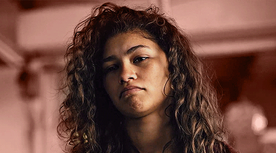 A gif of Megan Thee Stallion with her fingers forming a V against her tongue which she wags playfully.